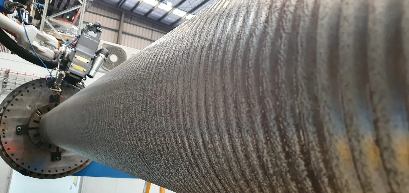Robot applying weld cladding to a tapered vessel